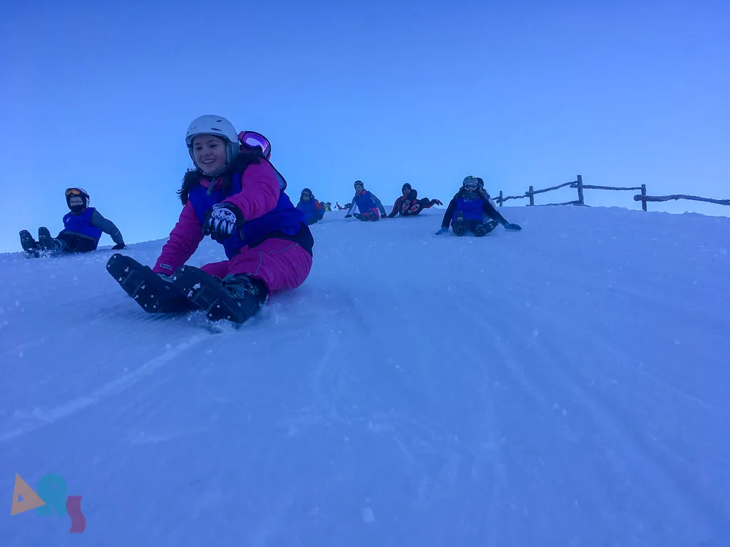 Jugendliche machen Pause auf der sonnigen Schneekuppe.